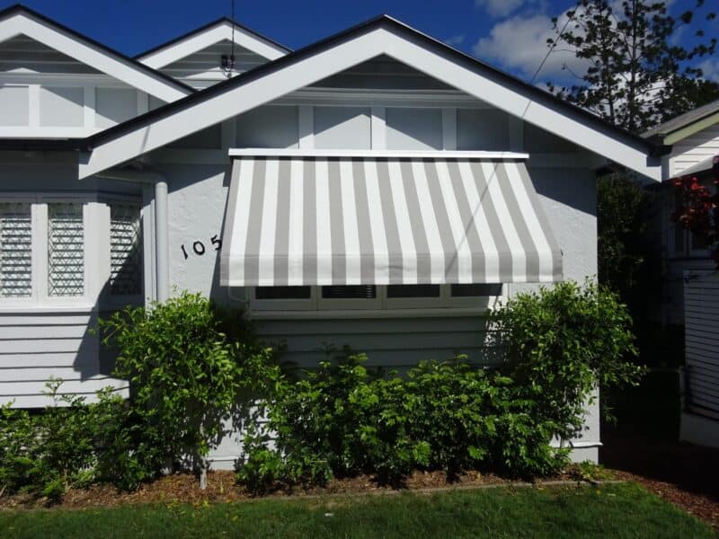 Grey house with white and grey striped awning